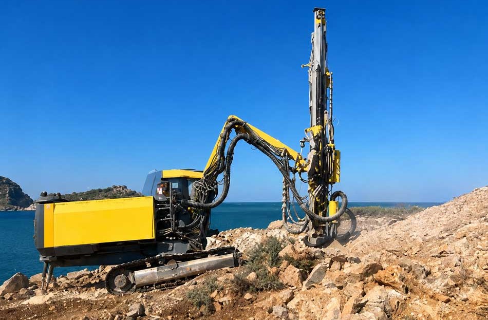 DTH-drilling-rig-in-operation-showing-hammer-and-bit-assembly-drilling-into-rock-formation-at-job-site.jpg
